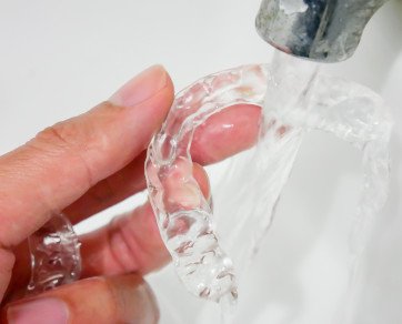 Rinsing off an Invisalign clear aligner in Fort Worth, TX