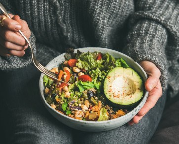 Close-up of person in sweater eating a salad