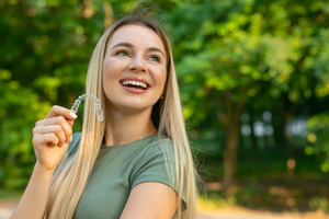 Blonde woman holding a clear aligner